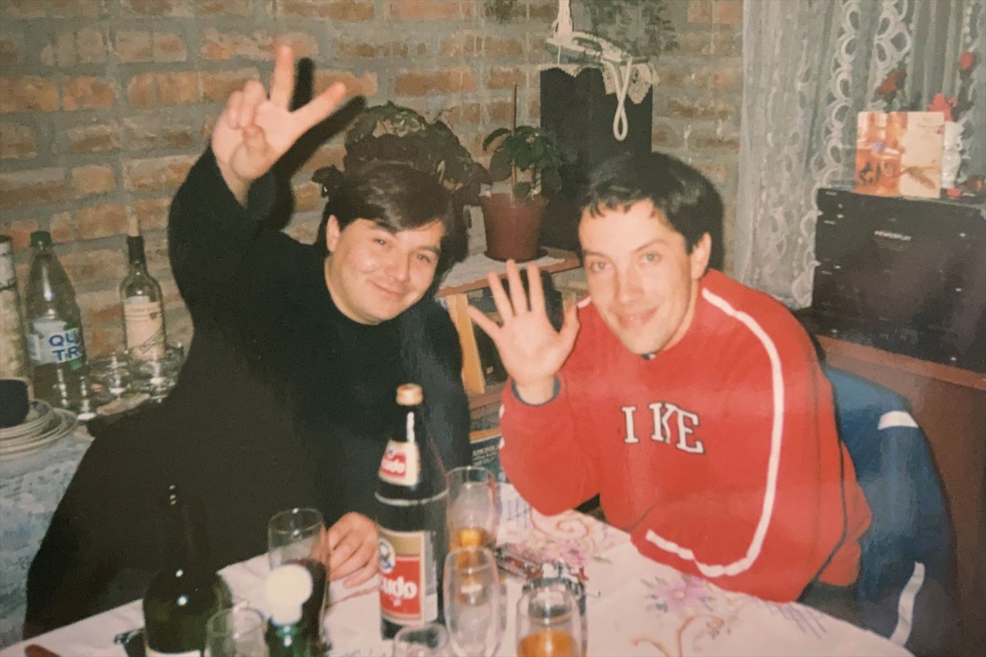 Chuck y el Guatón sentados a la mesa, saludando a la cámara, en una foto de los años noventa