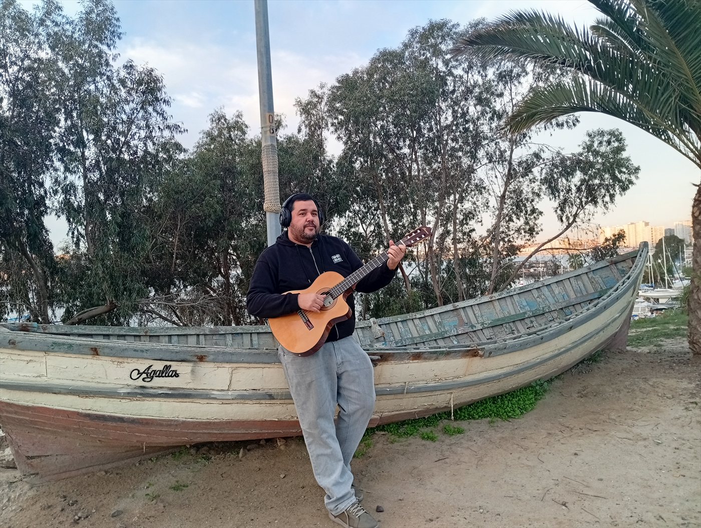 Petoro apoyado en un bote varado, con su guitarra